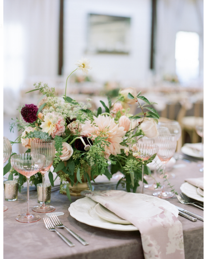 Summer wedding centerpiece  tablescape with a color palette of blush dahlia and burgundy ranunculus.